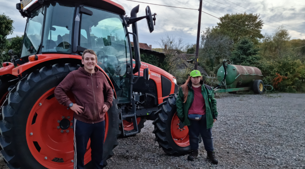Two members of staff standing in front of a tractor at the tree nursery