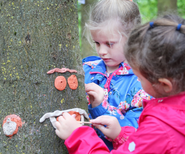 A couple of children playing with crafts in the woods together