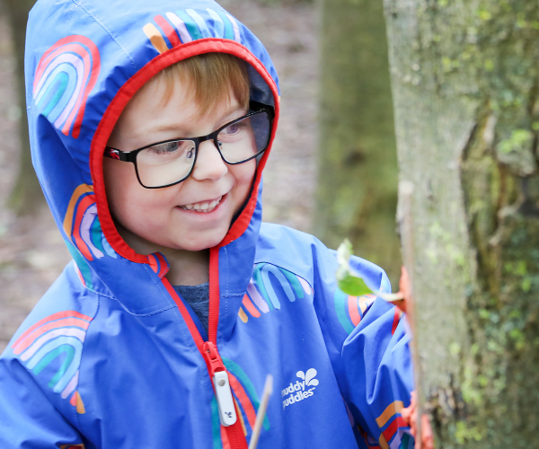 A child smiling whilst looking closely at a tree in the Forest