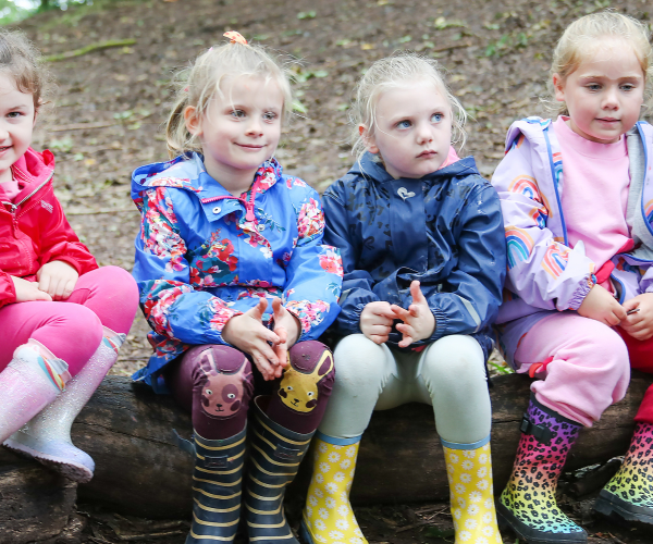 A group of children sat together on a log in the Forest