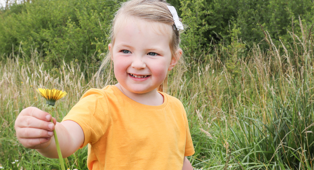 Child holding a yellow flower