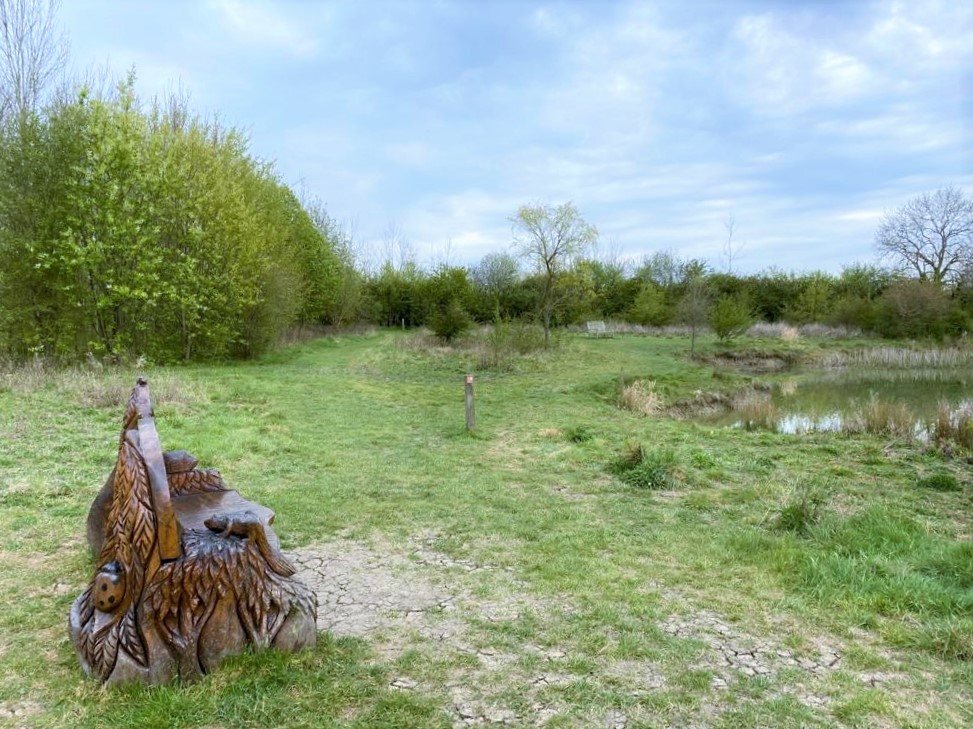 The wooden carved bench next to Colletts Pond
