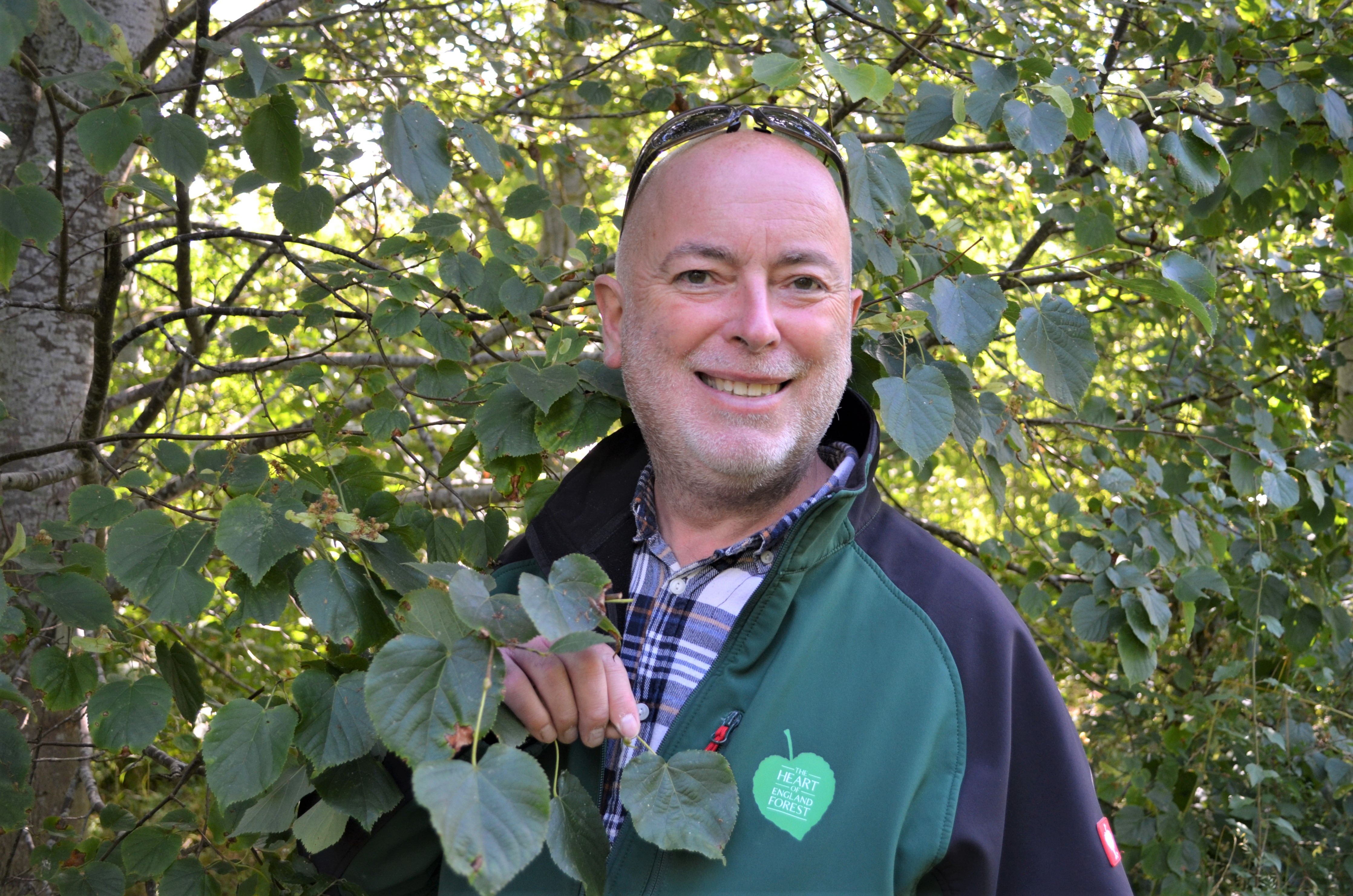 Phil with a heart-shaped leaf and his Heart of England Forest branded logo