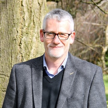 Steve Price standing outside by a tree