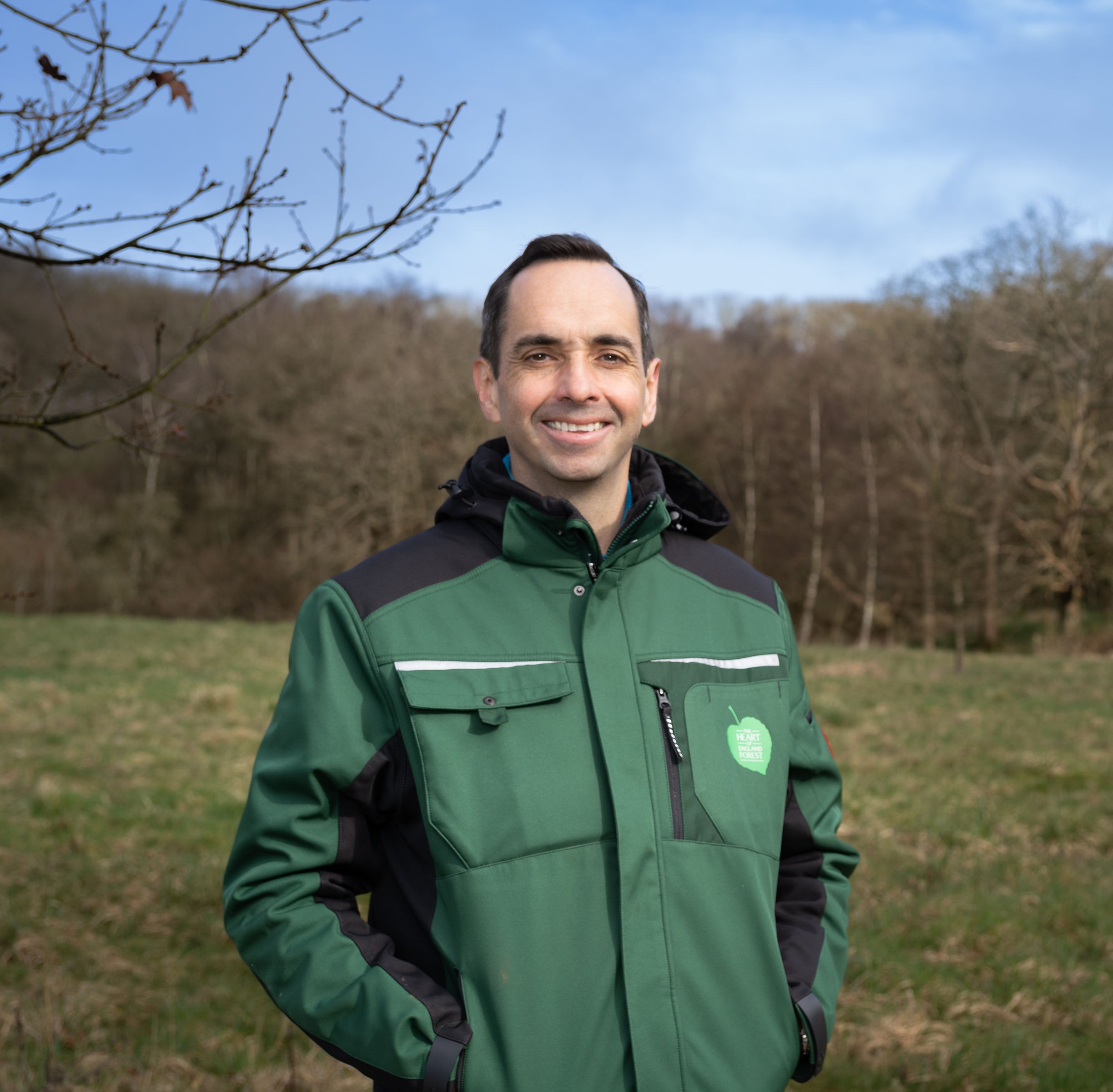 James Booth - Alne Wood Park Manager smiling at the camera. The natural burial ground is in the back ground