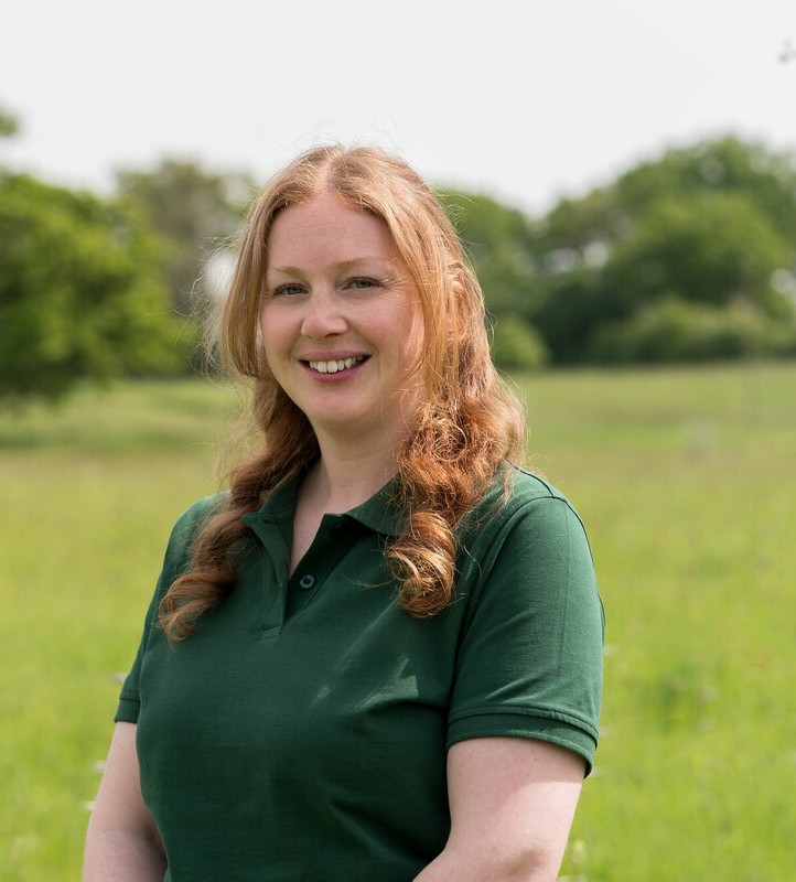 A headshot of Fay Cowie smiling at the camera in a branded tshirt