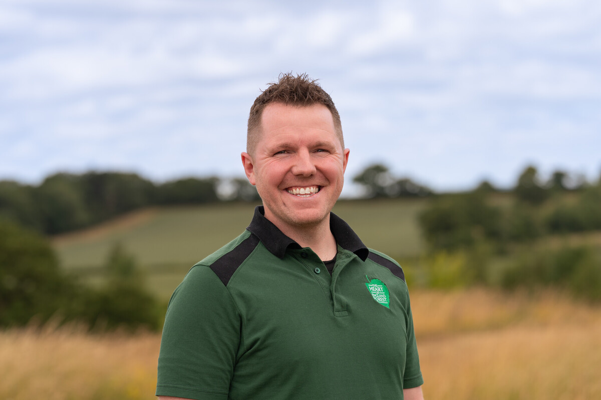 A picture of Ben smiling at the camera in a branded tshirt