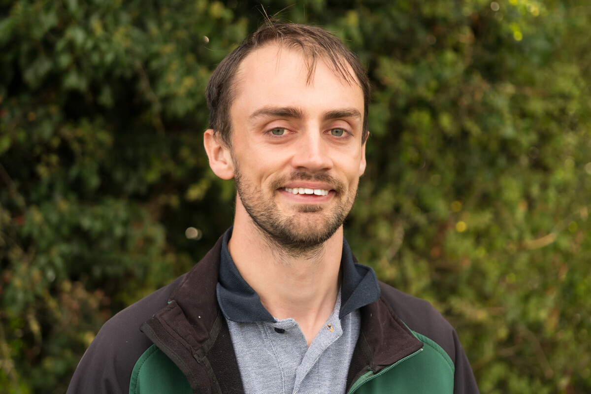 Sam Macvie, smiling at the camera. Head and shoulders professional shot. 