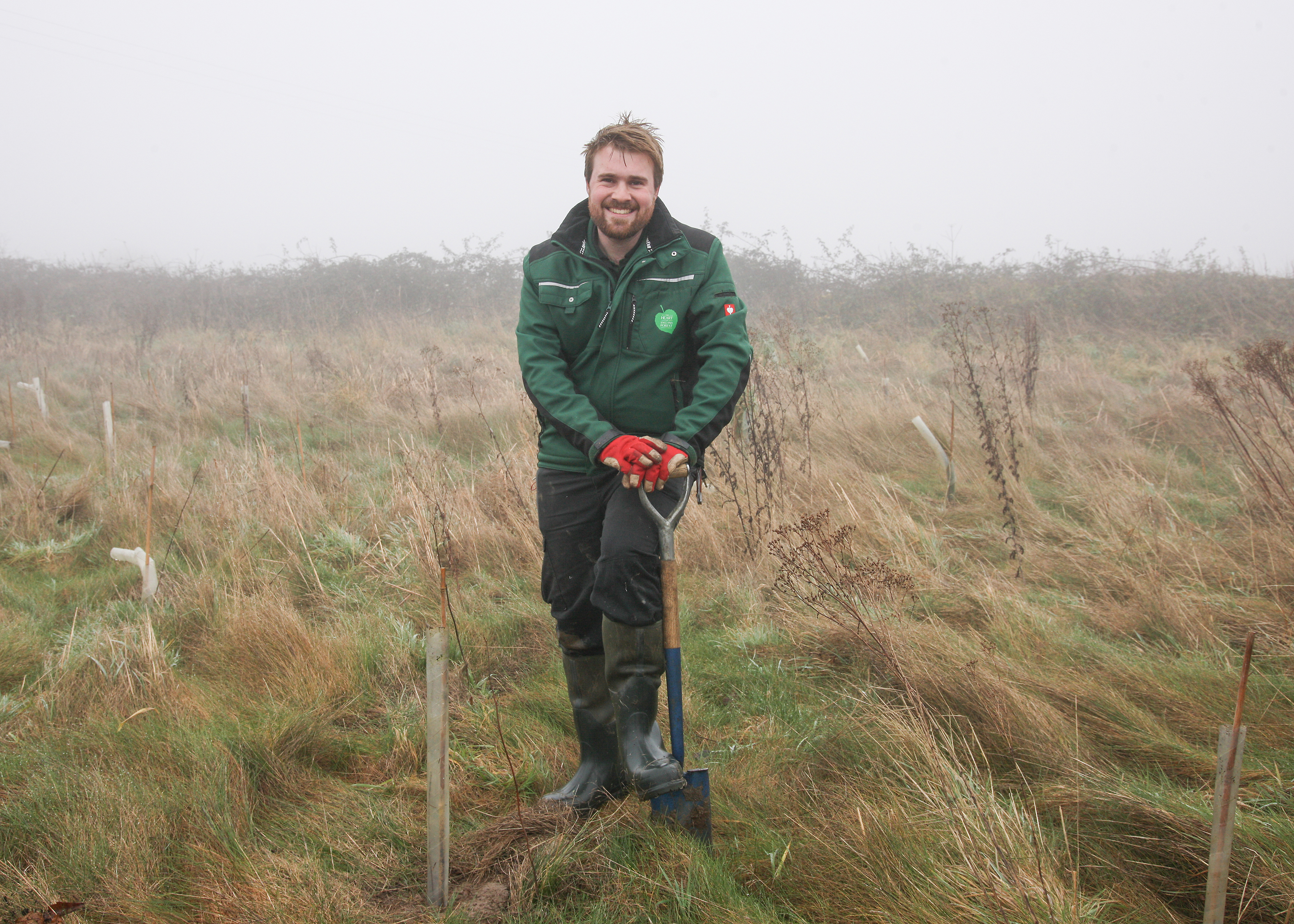 A smiling photo of Jonathan in the Forest about to plant a tree