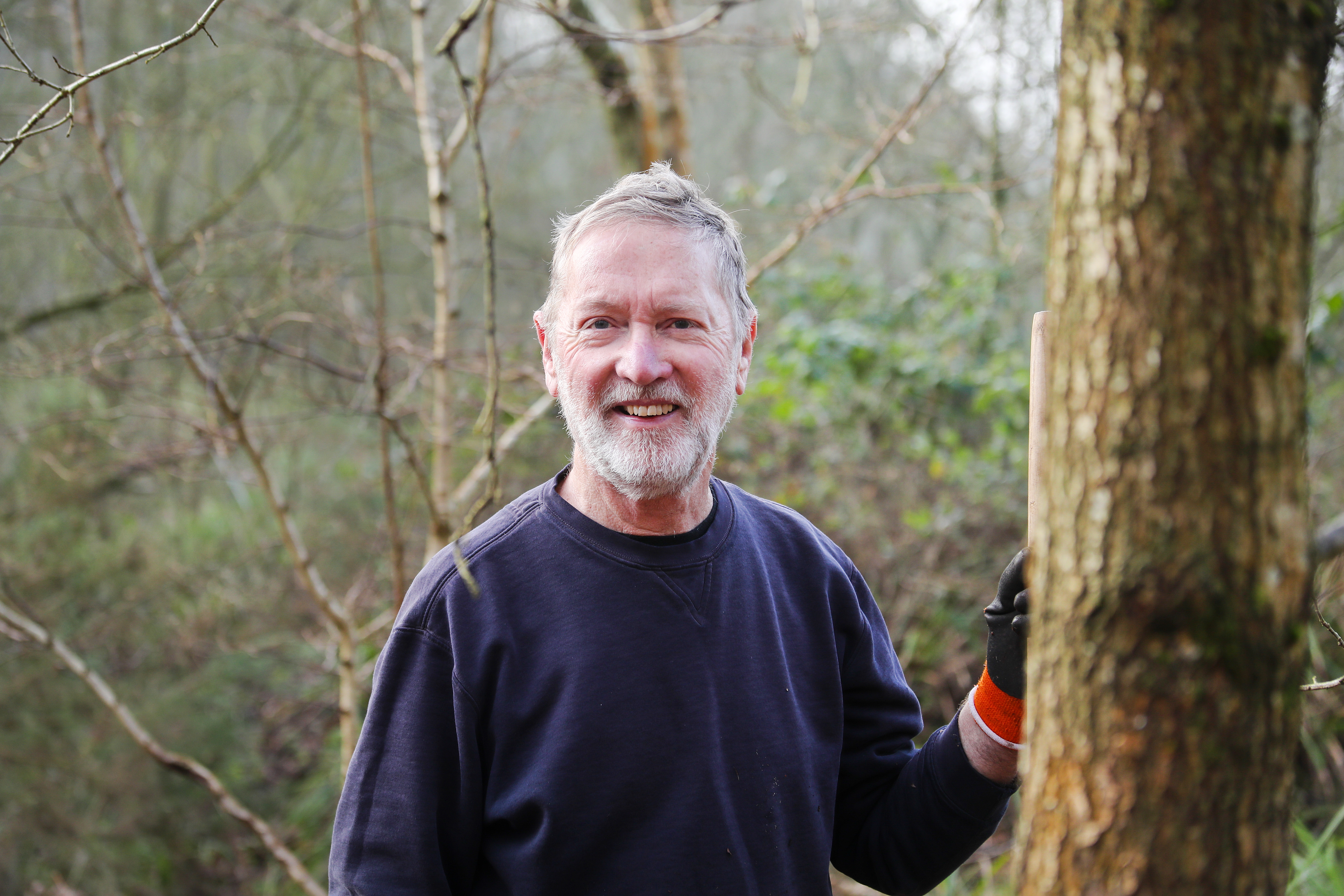 A male volunteer learning on a tree