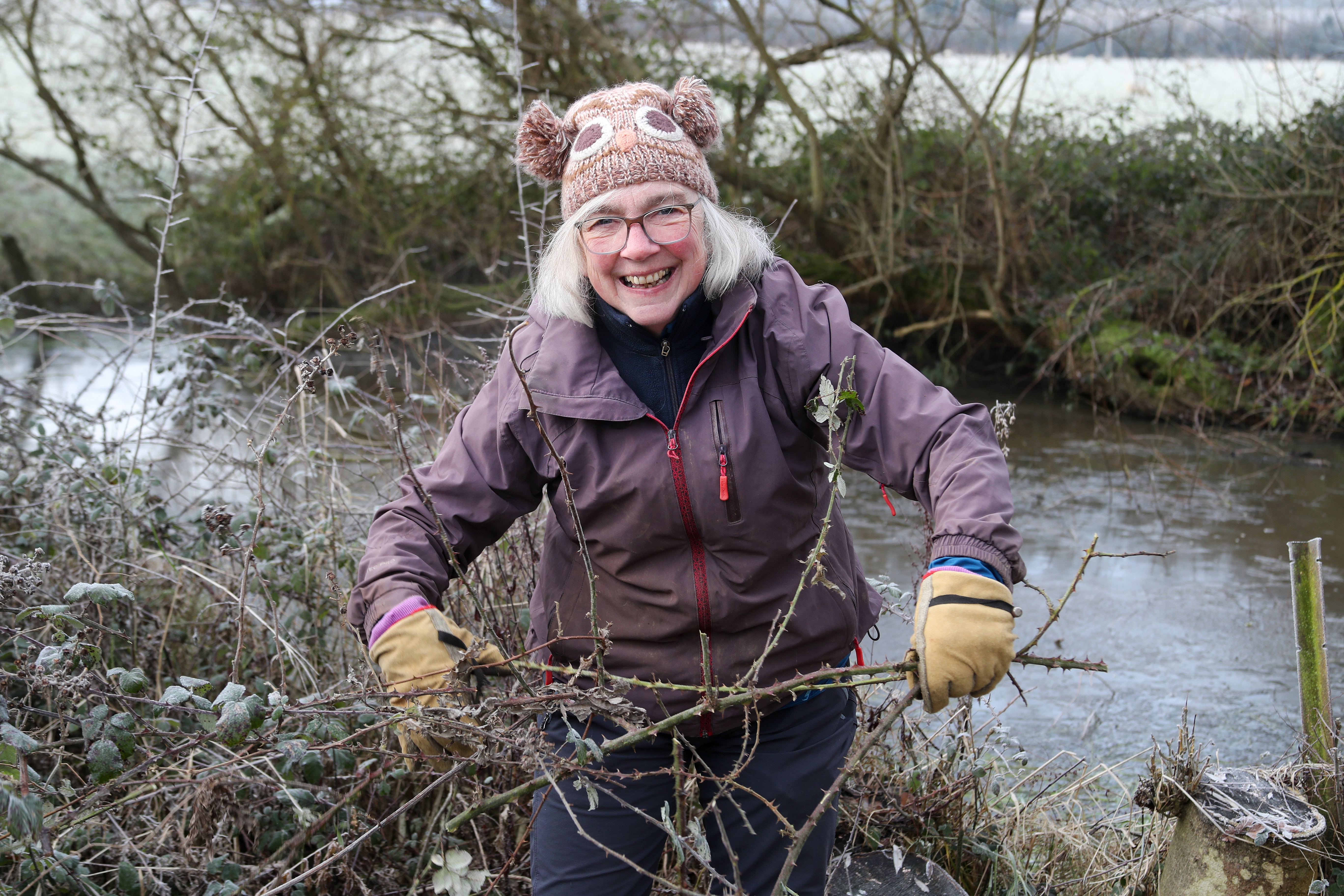 Volunteer Ann, cutting bramble down from the edge of the pond to clear open spaces for wildlife.