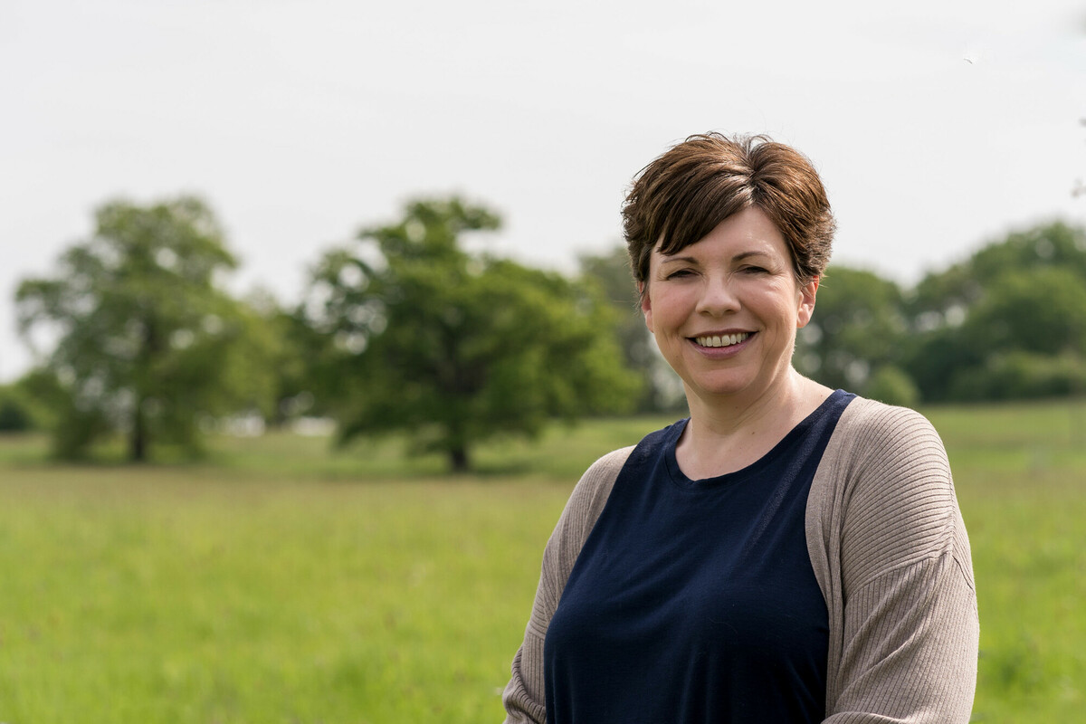 Alison Hunter head and shoulder shot, summer scene green trees in the background