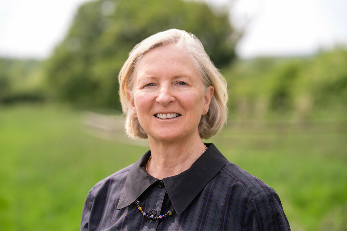 A head and shoulder shot of Heather Acton, there is a green hedge in the background