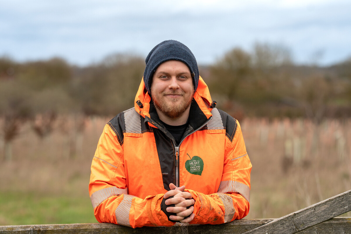 Forestry Works Manager (Spernal) James Poppleton smiling at the camera wearing an orange branded hi vis jacket 