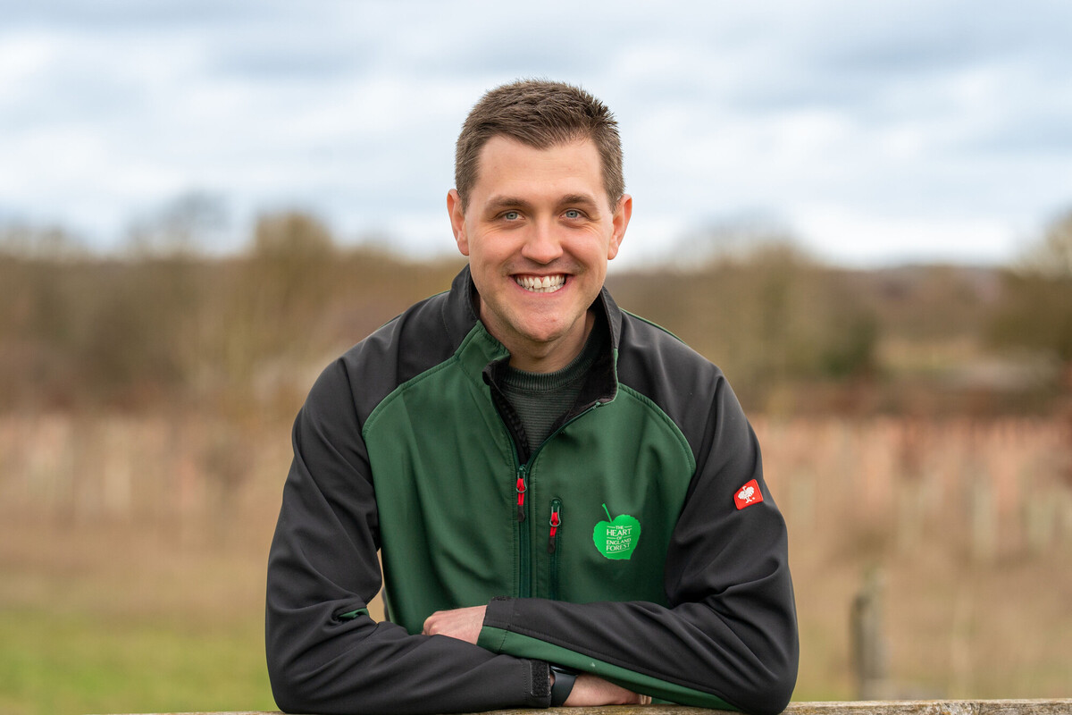 Andrew White smiling at the camera, wearing a  branded jacket 