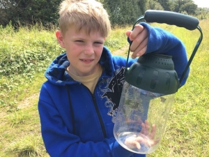A boy holding a container for catching butterflies in