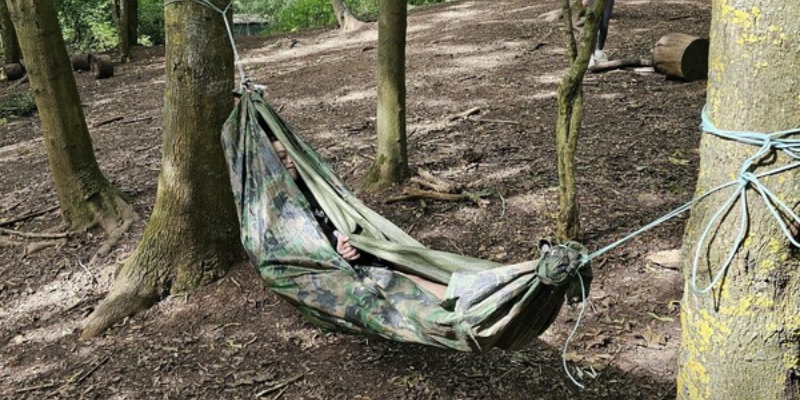 A child swinging in a hammock in the woods