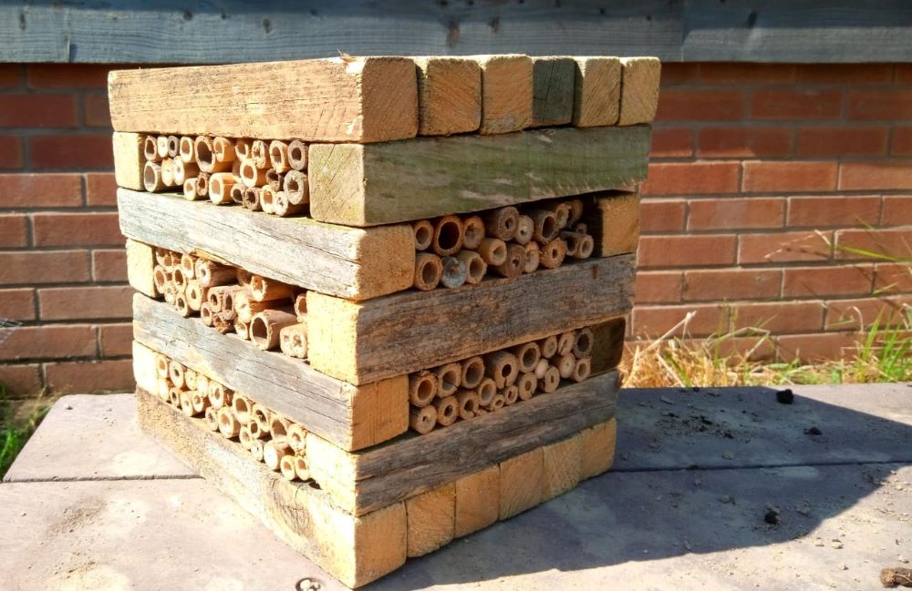 Close up of a homemade square bug hotel placed on a wooden top outdoors