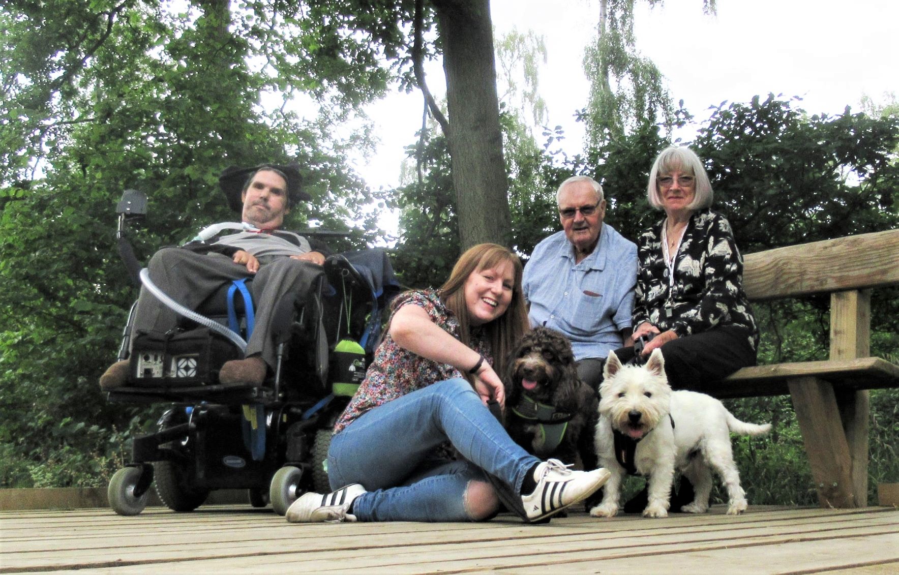 Wheelchair user Paul with his family and dogs on the boardwalk on accessible trail 