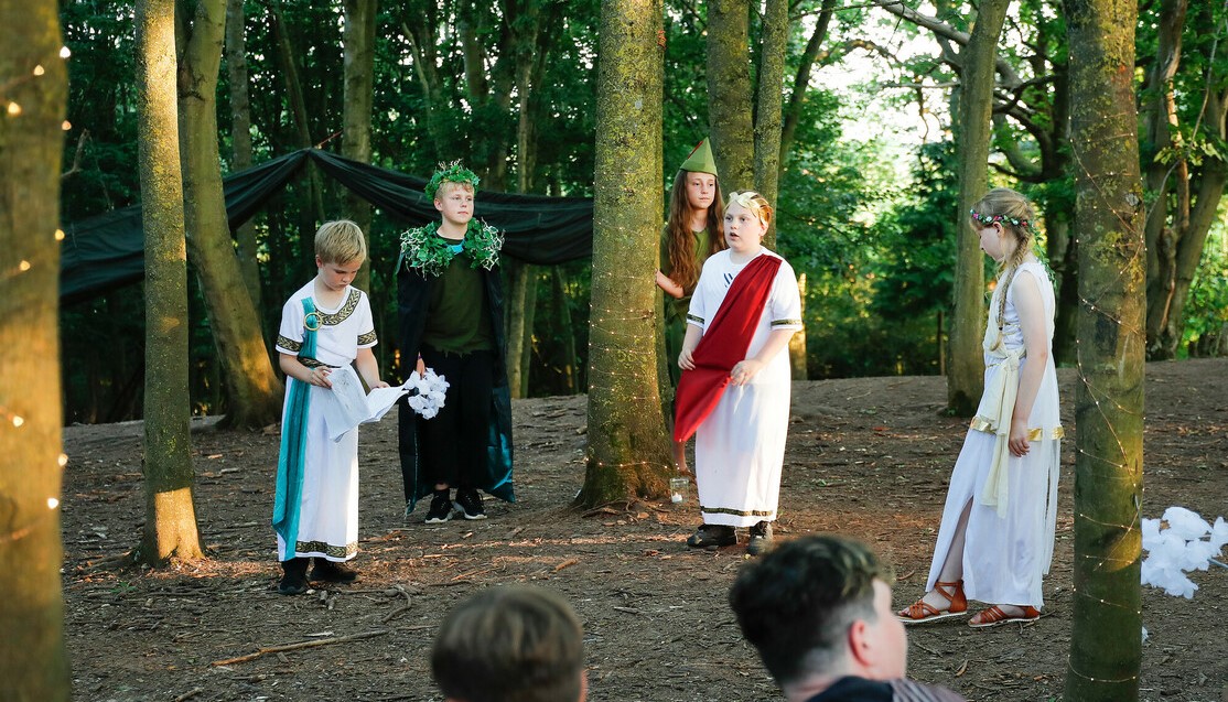 A group of pupils perfoming A Midsummer Night's Dream amongst the trees