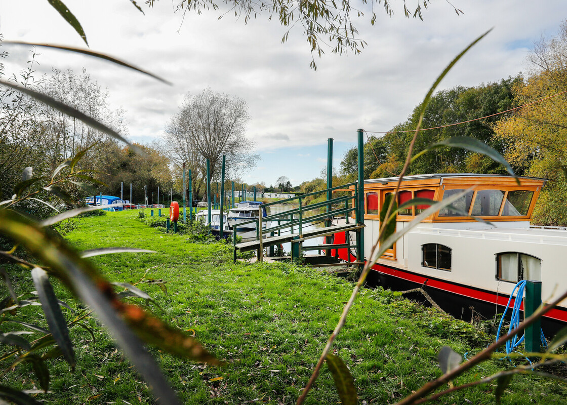 Close up of grassy river bank and boats moored on the River Avon at Dovecote Moorings