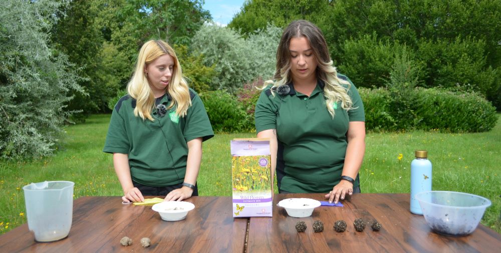 Ellie and Tasha making seed bombs on a table outdoors in the Forest