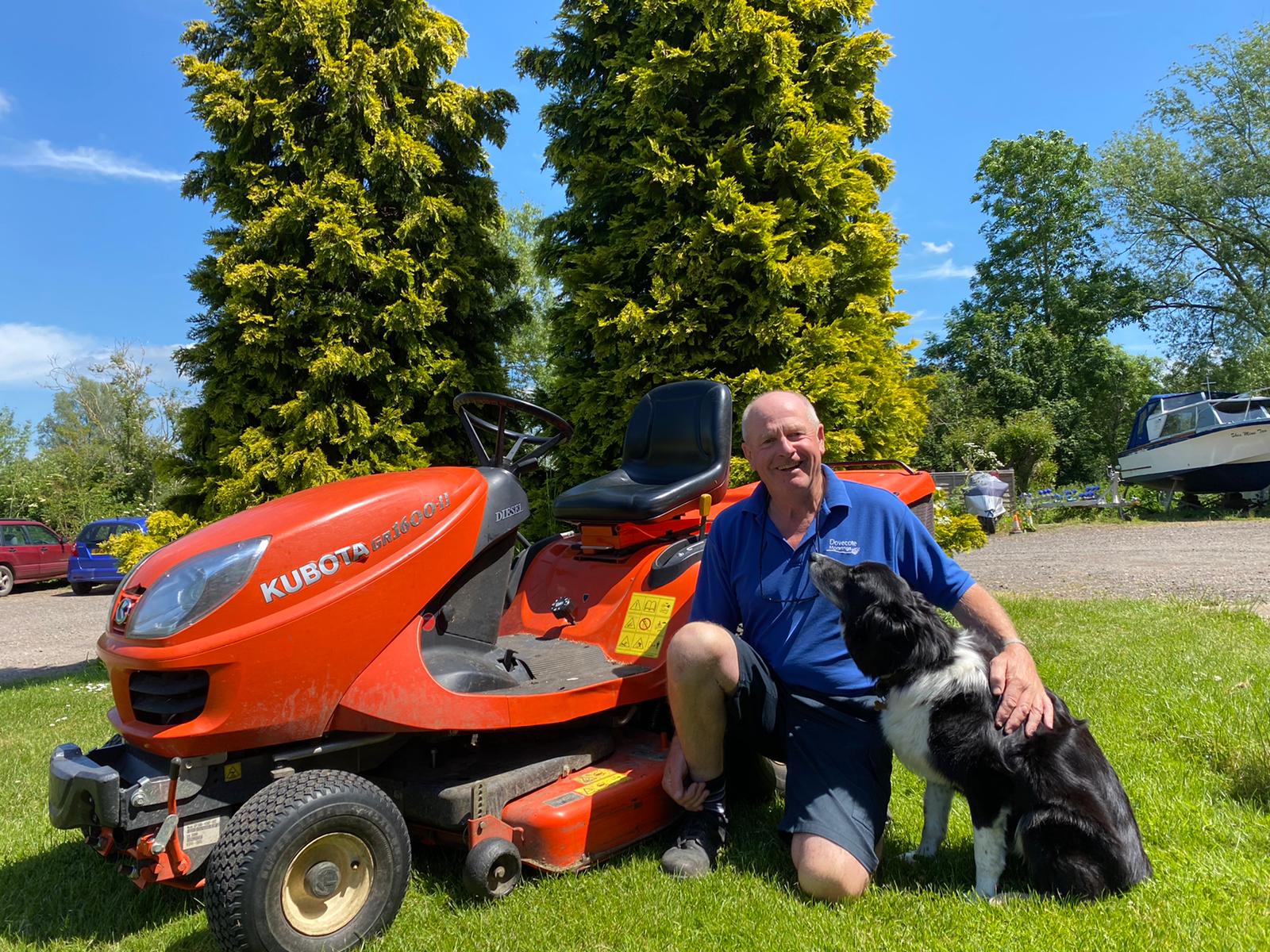Mark crouching next to a red tractor with his black and white border collie Charlie.