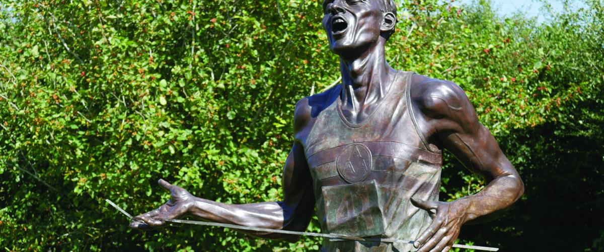 Close up of bronze statue of Sir Roger Bannister crossing the finish line 