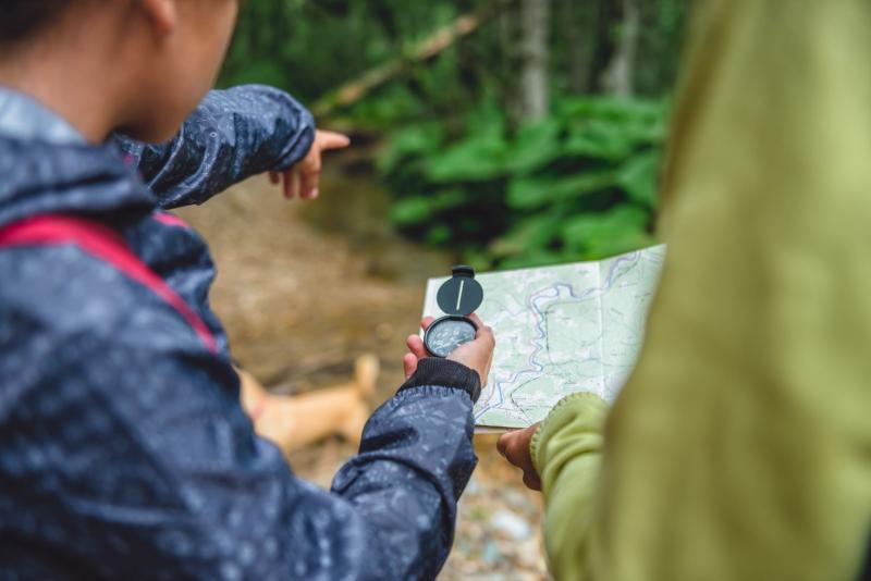 Close up of two people using a compass and map to navigate their route