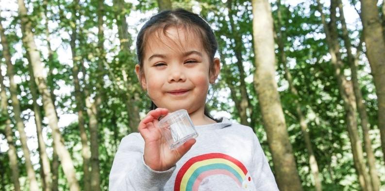 A young forester holding a plant in a plastic container