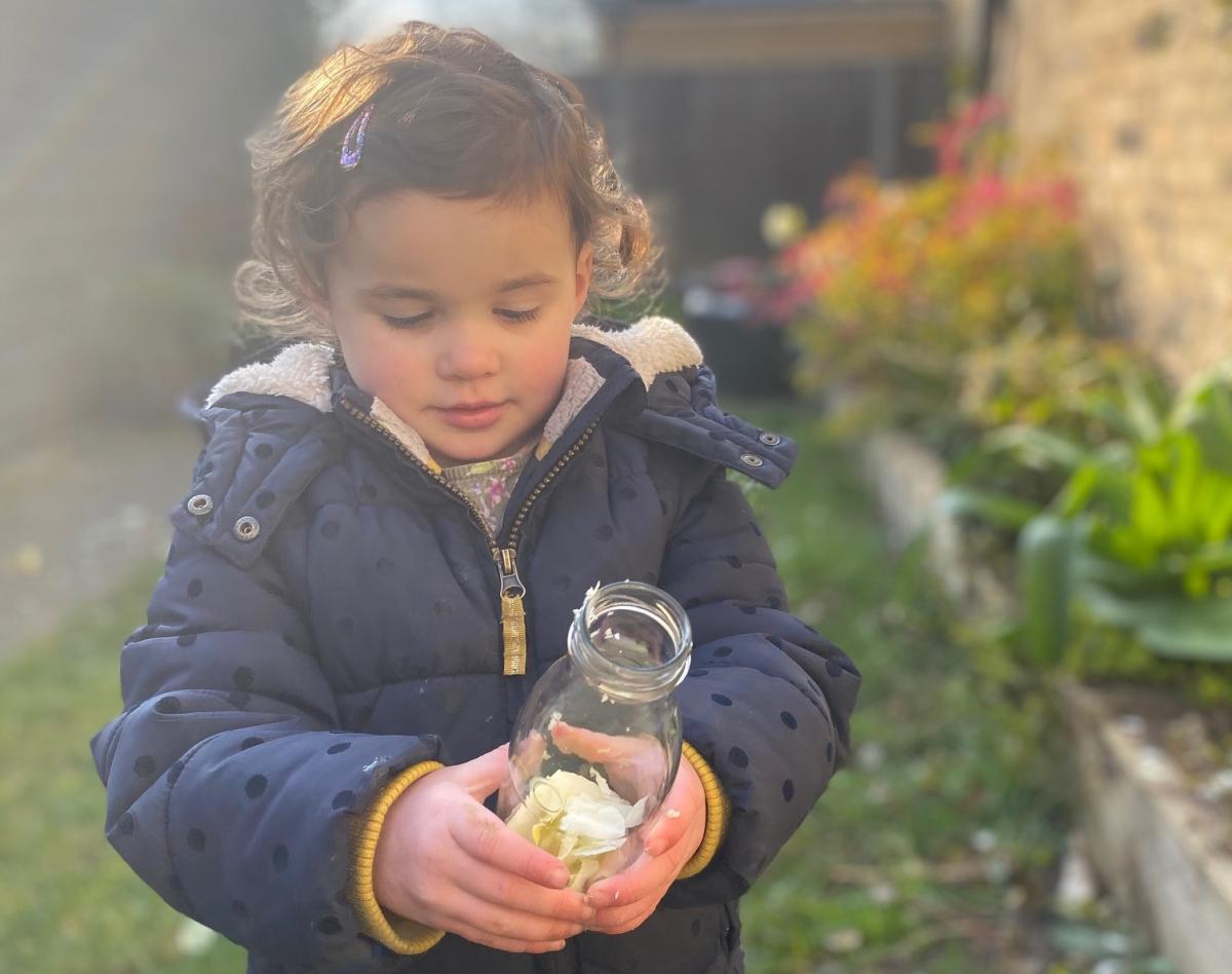 A young foresters holding a glass bottle full of petals