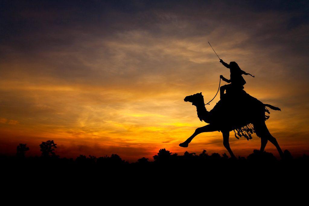 the sun setting over Lawrence of Arabia riding his camel