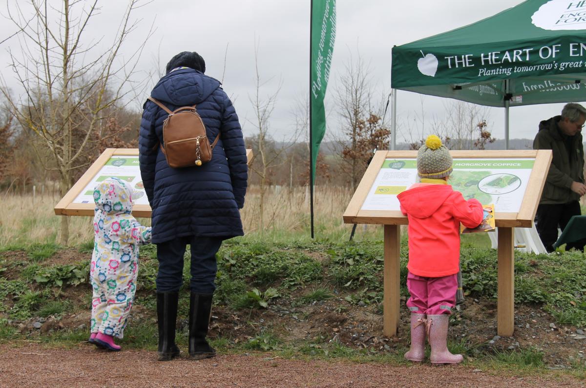 A lady and two children looking at a map board at the start of a Forest walk 
