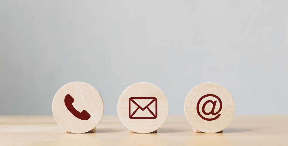 Phone, mail and email symbols on wooden disks in a line on a desk 