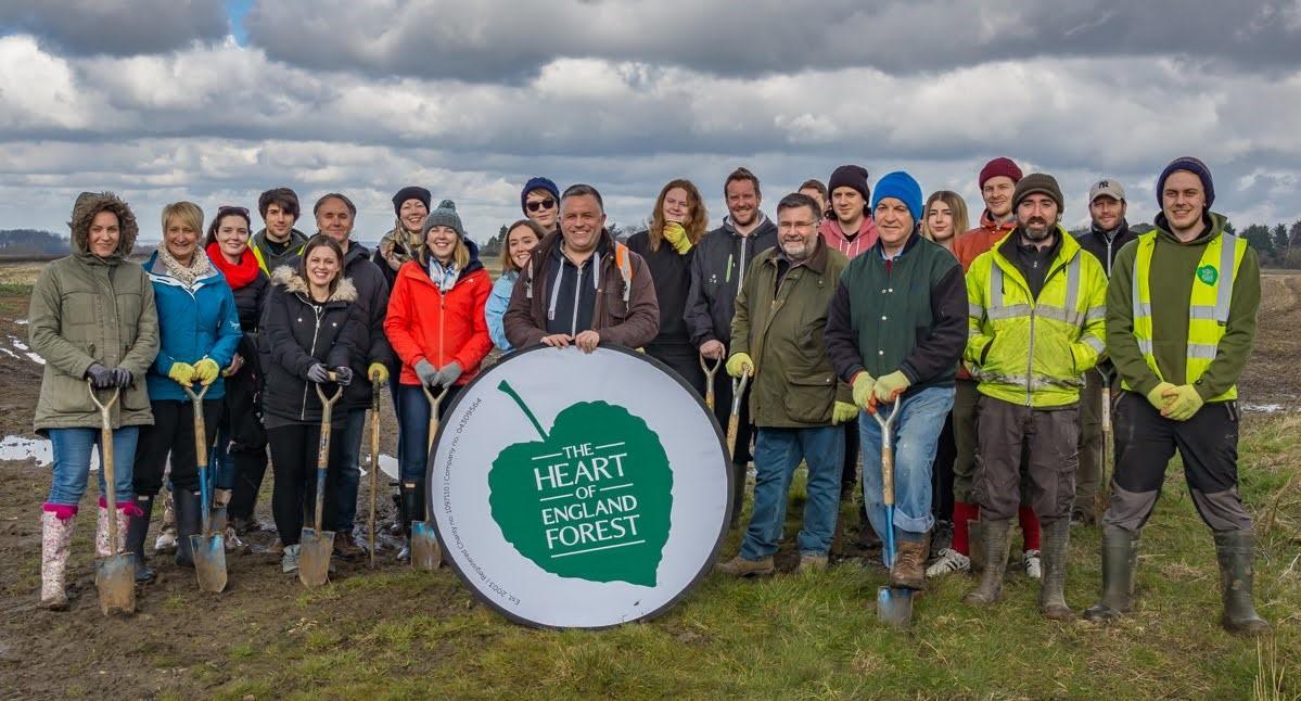 Big corporate group standing together after tree planting with some of our forestry team