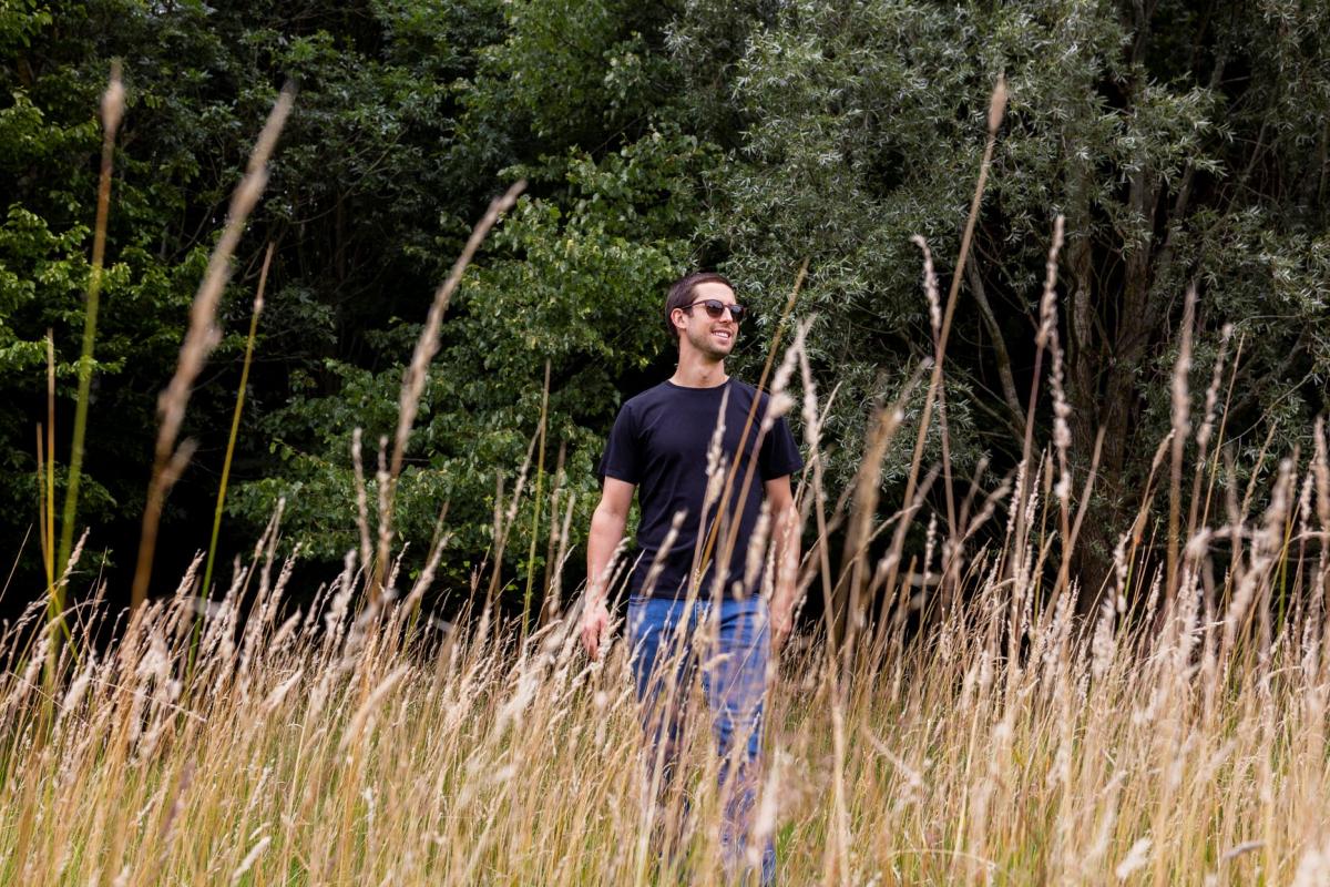 Alexander Sims standing in grassland in the Forest wearing sunglasses