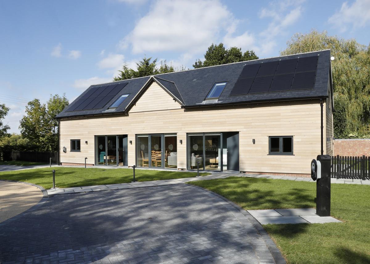 The outside of the new holiday lets. The black roof is fitted with solar panels and the light front wall is broken up by three big windows.