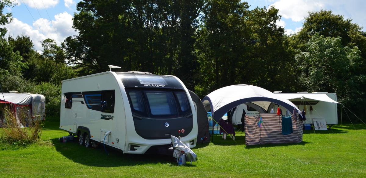 Three caravans with awnings pitched on the grass on a sunny day at Dovecote Moorings
