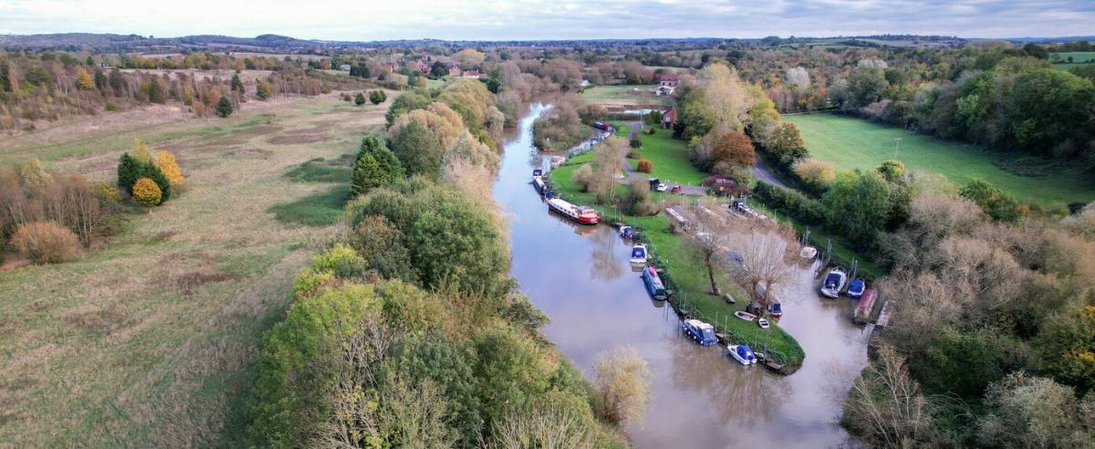 Aerial view of boats on the River Avon at Dovecote Moorings with the autumnal Forest surrounding it