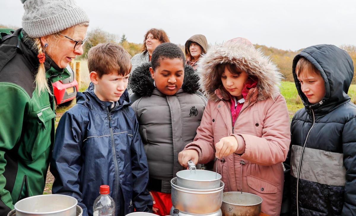 Four school pupils gathered around a trangia doing outdoor cooking with a member of the Fores team