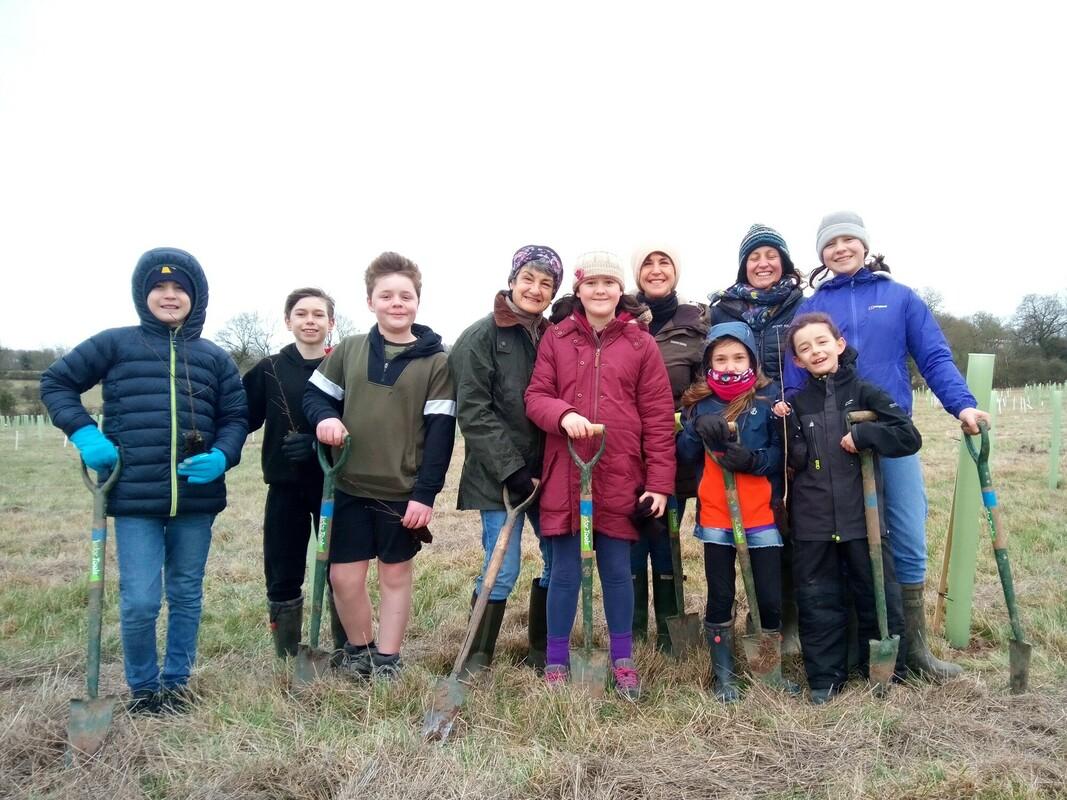 a group of adults and children holding shovels at the bearley community planting event