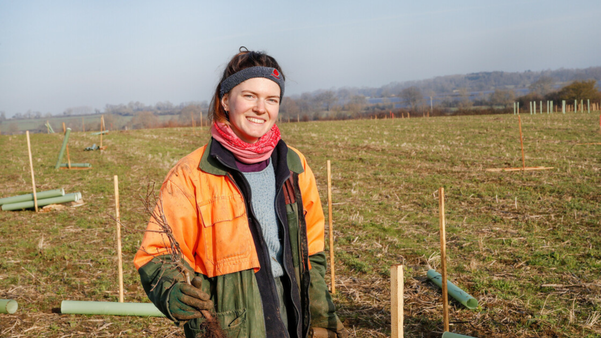 Fiona stood smiling in an open field during tree planting season