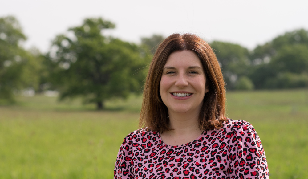 A head and shoulders photo of Becky Donnelly taken with grass and trees in the background. Heather is smiling at the camera