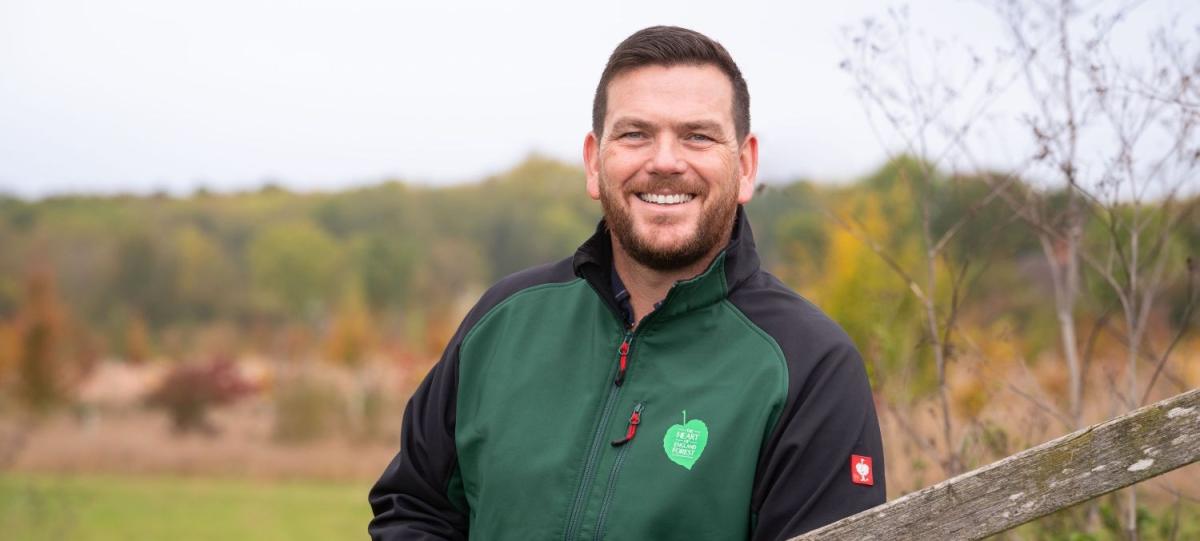 Head and shoulders shot of Andy Parsons, the charity's Chief Executive, standing by a gate with fields and trees behind him 