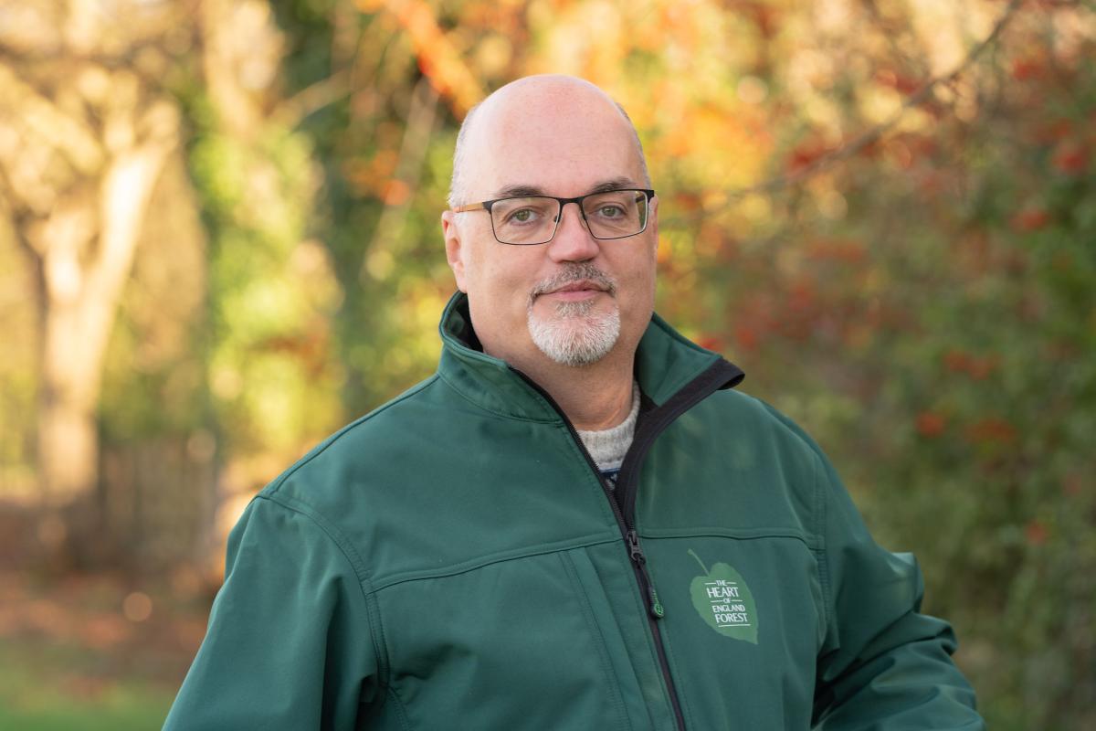 Trustee Jonathan Smith, looking at the camera, with lovely autumn trees blurred in the background.