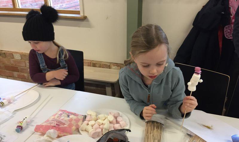 Two girls making marshmallow snowmen