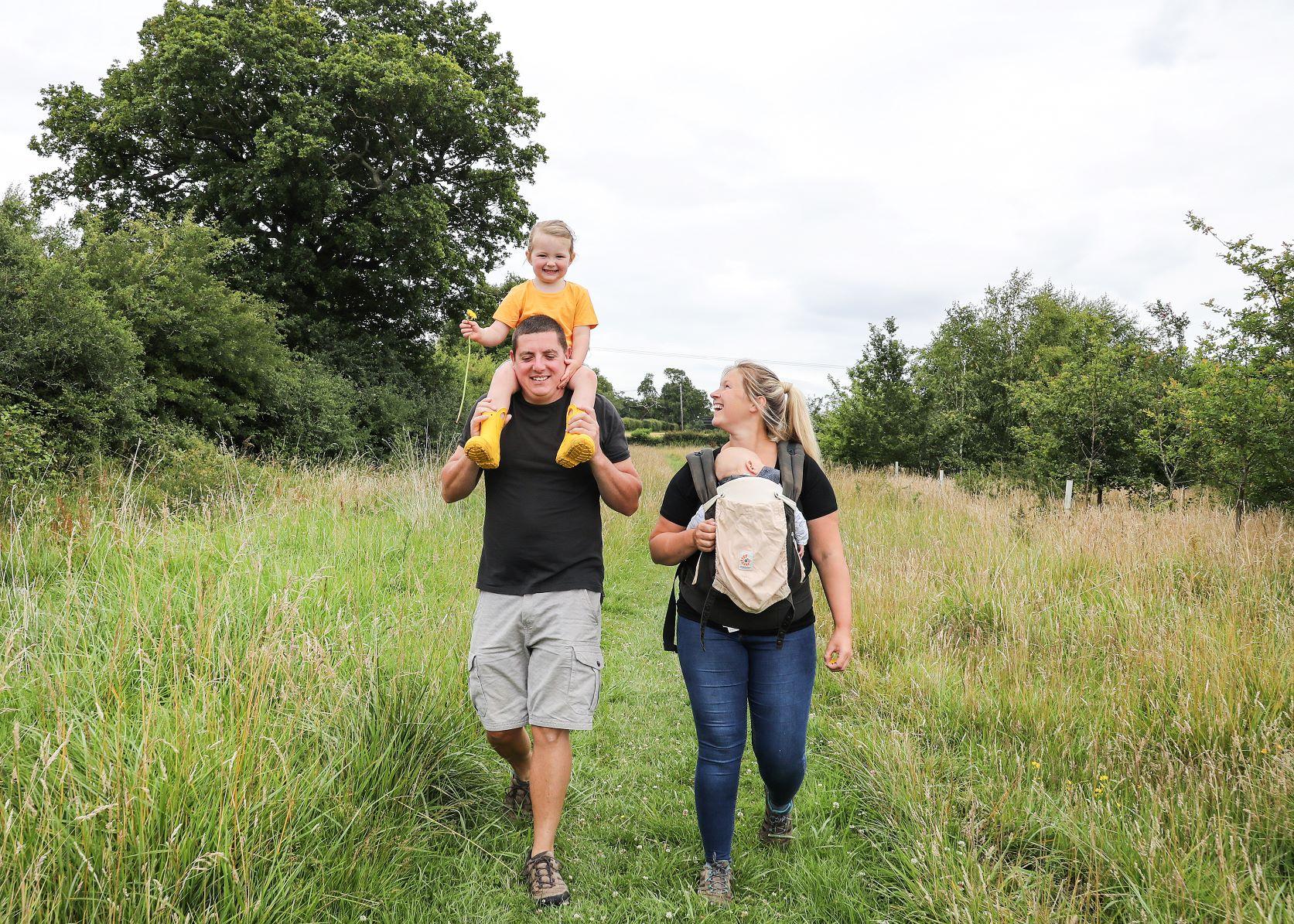 A family of four laughing and walking through the forest