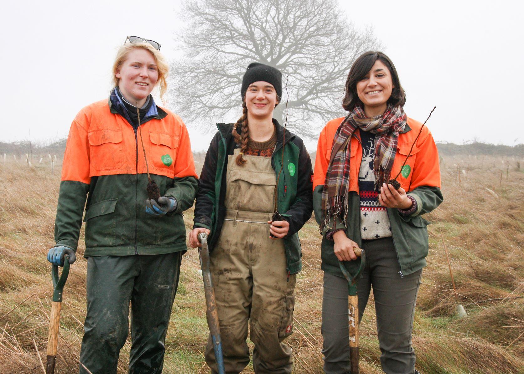 Three female members of our forestry team standing in a tree-planting field