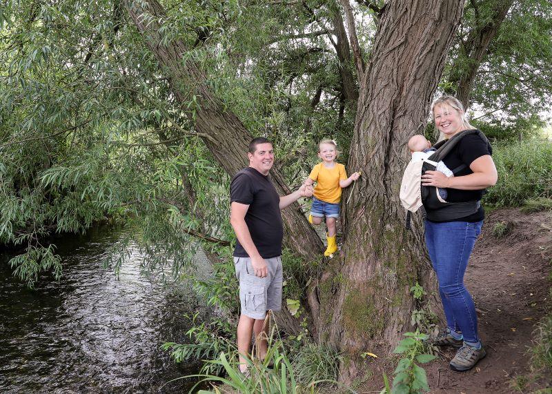 A family standing by a river in the Forest and smiling at the camera