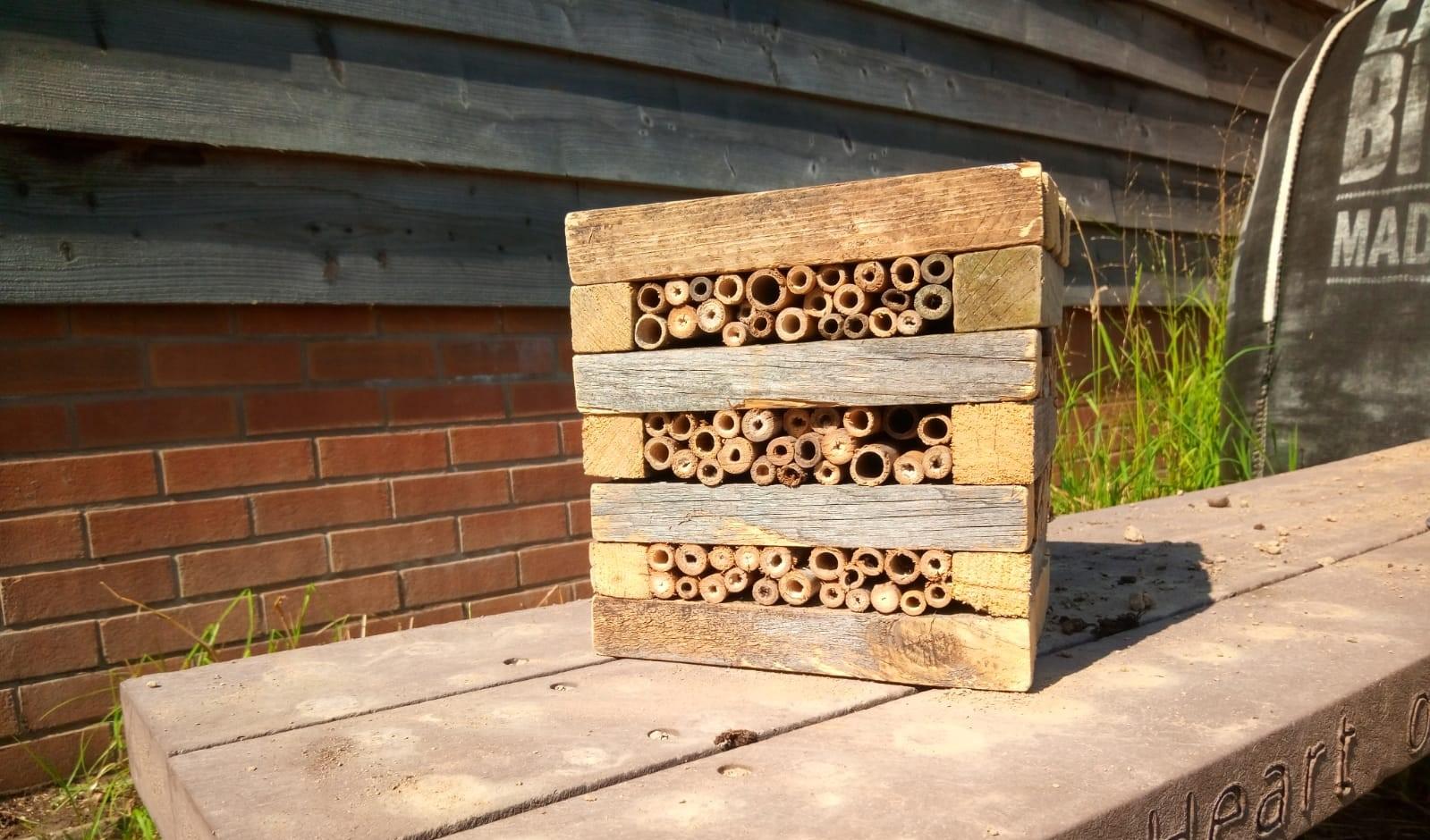 Handmade bug hotel sits on a wooden table on the right hand side. 